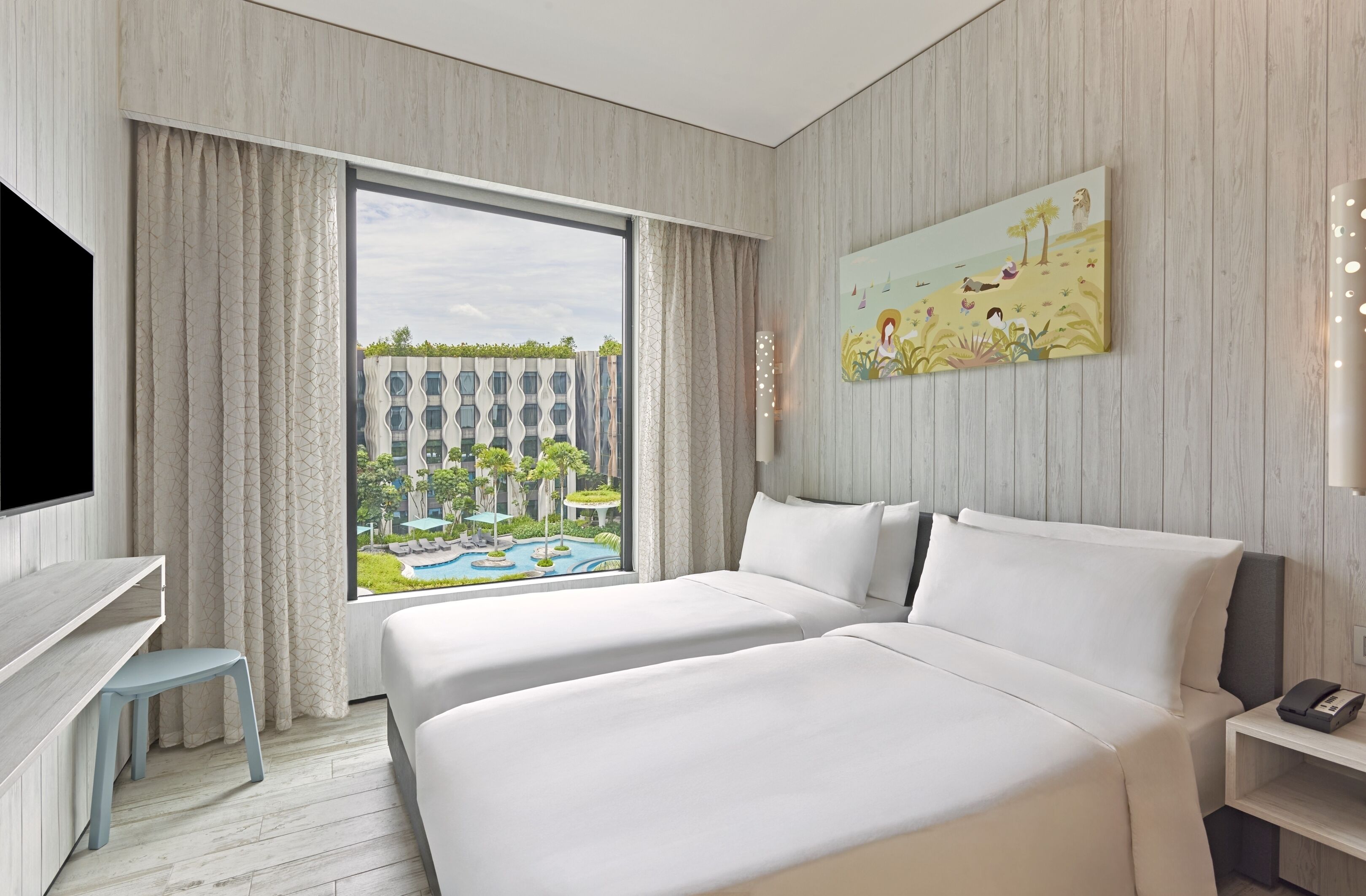 A hotel room with a large window, two beds, a desk, and a painting.