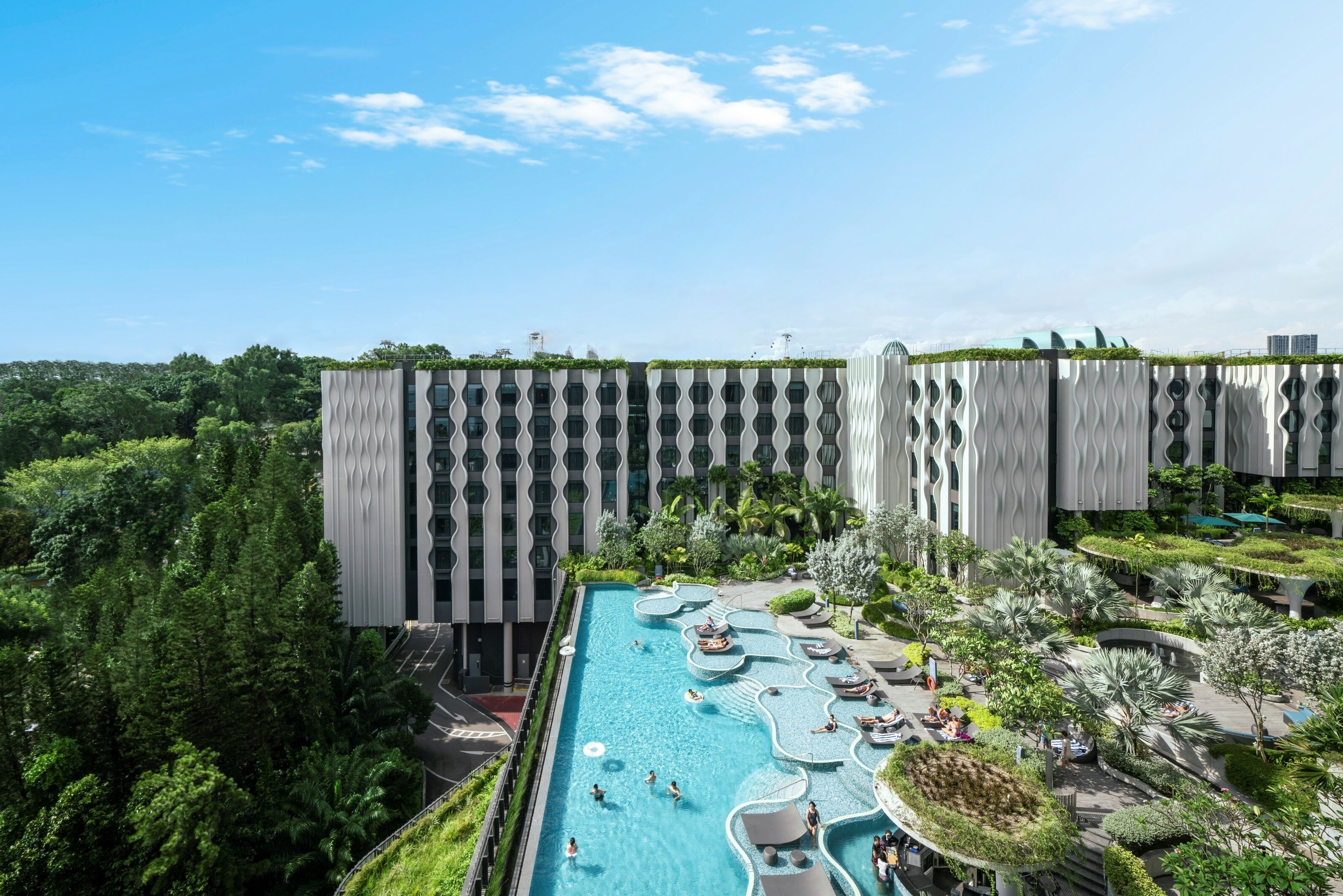 Un hotel moderno con piscina en la azotea, rodeado de exuberante vegetación y un diseño arquitectónico único.