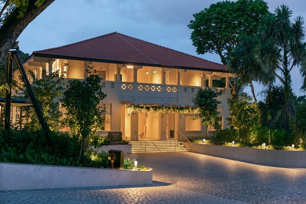 A hotel with a red-tiled roof, a covered entrance with stairs, and a landscaped garden area. - Village Hotel Sentosa by Far East Hospitality (Singapore)