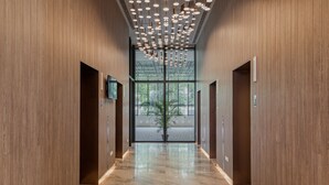 Un pasillo moderno con paneles de madera, suelo de mármol e iluminación colgante.