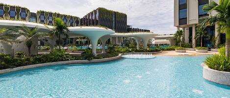 Una piscina con un diseño arquitectónico moderno, rodeada de exuberante vegetación y palmeras.
