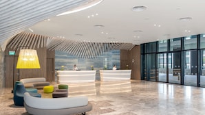 A modern lobby with a reception desk, seating area, and a large glass wall. - Village Hotel Sentosa by Far East Hospitality (Singapore)