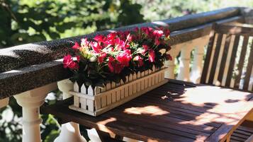 A wooden bench with a planter box containing red flowers on a balcony.
