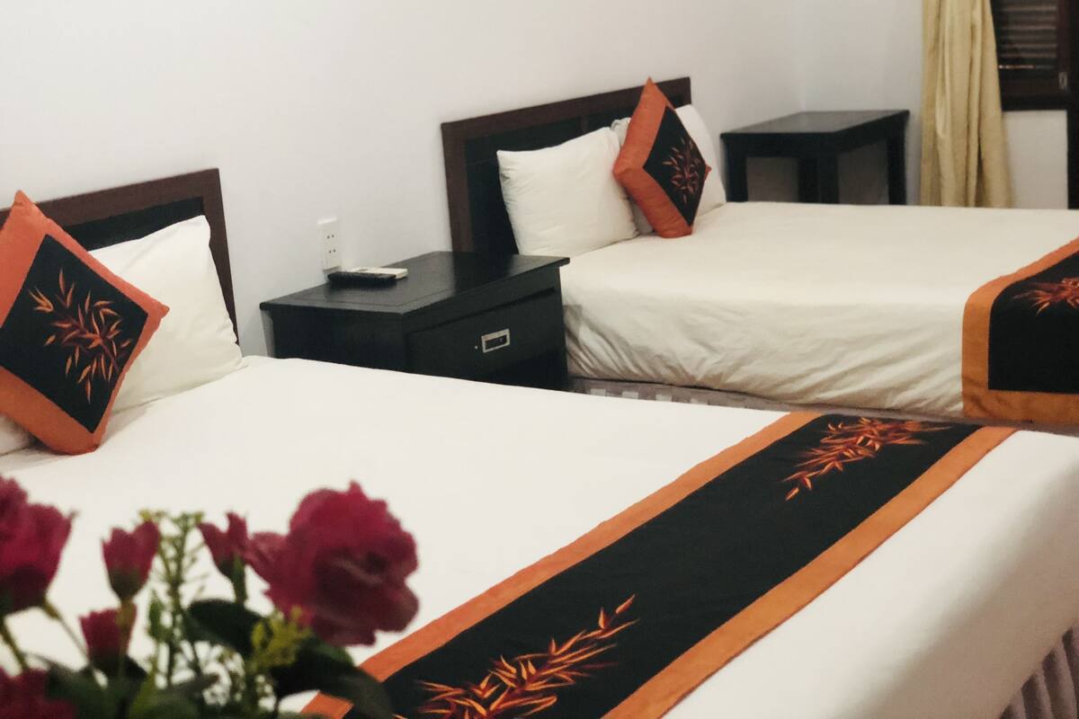Dos camas individuales con cabeceras y pies de cama a juego, una mesita de noche y otra mesilla.