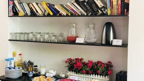 Una estantería con varios libros, una cafetera y un dispensador de agua.
