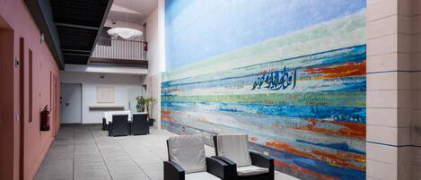 A modern lobby with a colorful abstract mural, seating area, and a staircase.