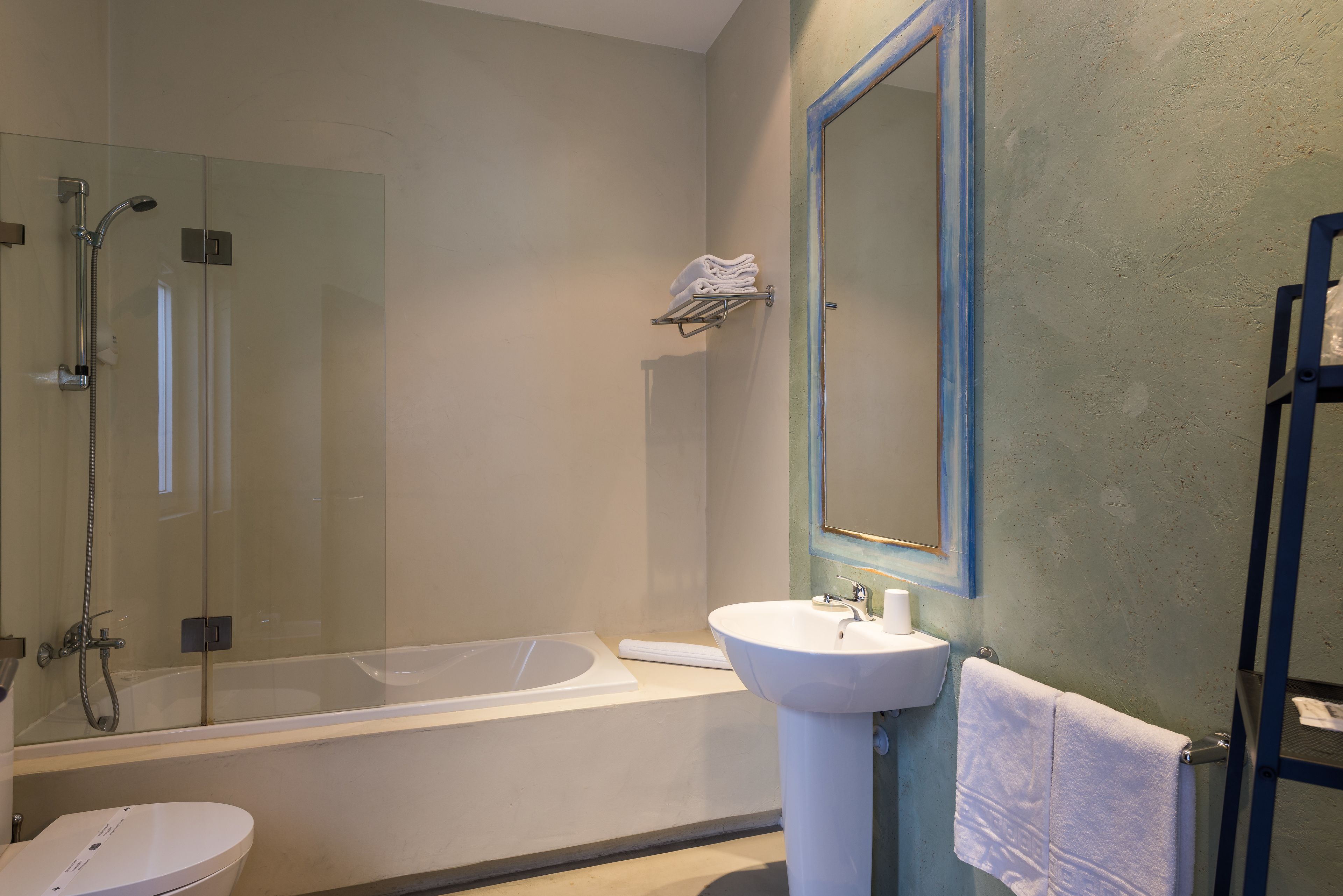 Une salle de bain moderne dotée d’une douche à parois de verre, d’une baignoire sur pieds, d’un lavabo sur colonne et d’un grand miroir.