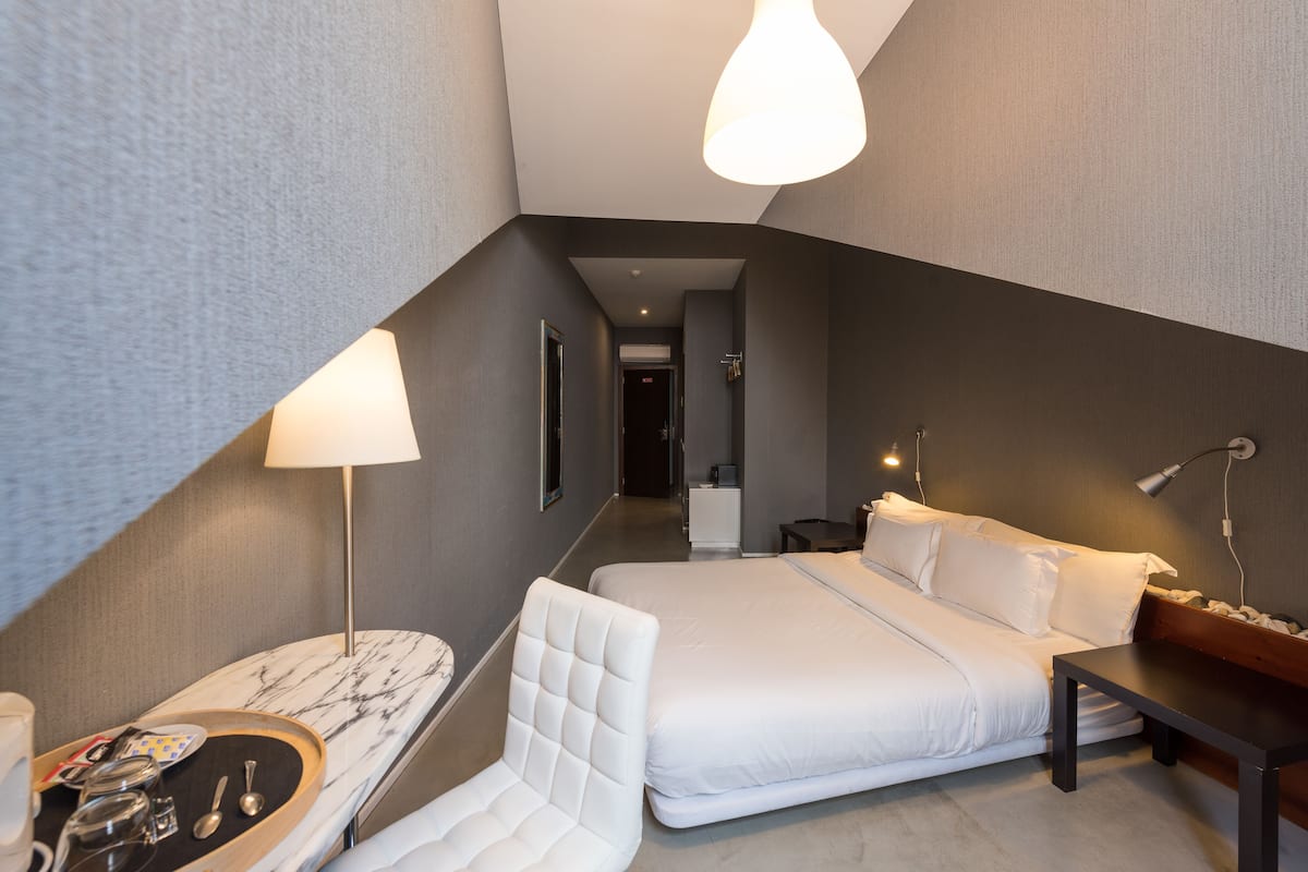 Una habitación de hotel moderna con una cama grande, un escritorio con silla y una mesita.