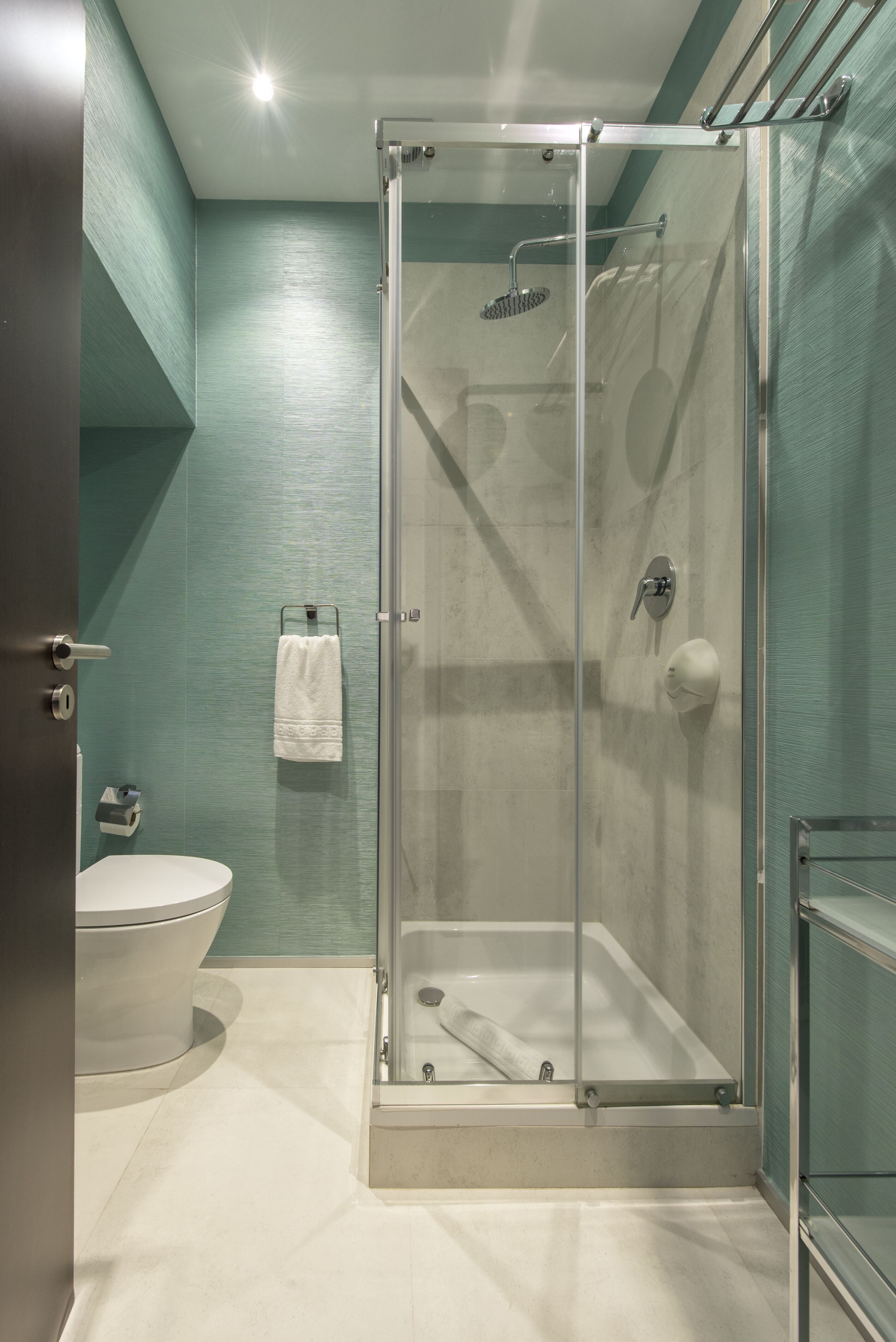 Un baño moderno con ducha envuelta en vidrio, inodoro blanco y bañera con cerramiento de vidrio.