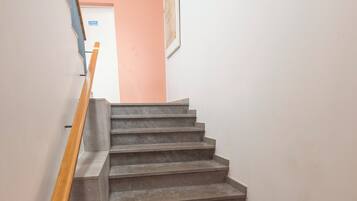 A staircase with a wooden handrail leading to a door at the top.
