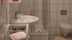 A bathroom with a sink, toilet, and shower. - Landgasthaus Veltheimer Hof (Porta Westfalica)