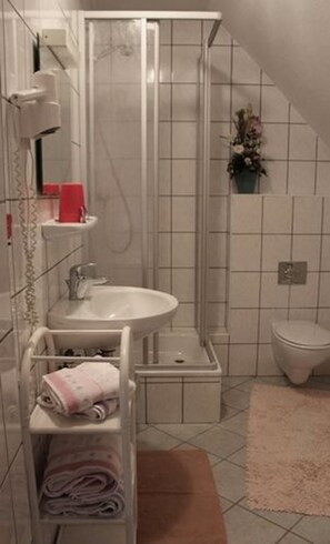 A bathroom with a sink, toilet, and shower. - Landgasthaus Veltheimer Hof (Porta Westfalica)