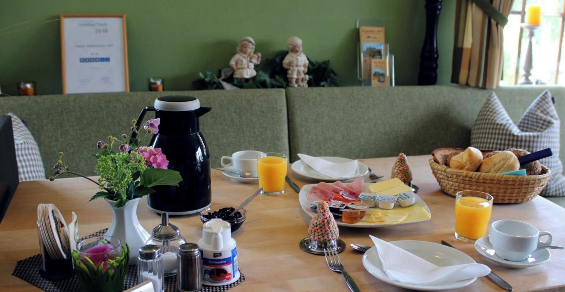 A breakfast setting with a coffee pot, eggs, toast, and juice on a table.