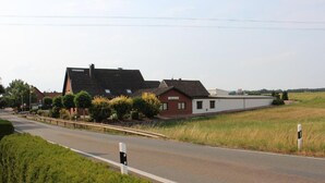 A rural road with houses on one side and open fields on the other. - Landgasthaus Veltheimer Hof (Porta Westfalica)