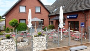 A restaurant with outdoor seating, a brick building, and a sign for 'Veltheimer Hof'. - Landgasthaus Veltheimer Hof (Porta Westfalica)