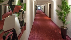 Un couloir avec un tapis rouge, des murs recouverts de miroirs et des plantes en pot.