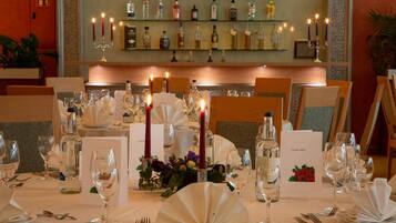 Ein Restaurantambiente mit gedeckten Tischen, Kerzen und einer Bar mit verschiedenen Flaschen.