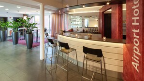 Un espace bar moderne avec un comptoir, des tabourets de bar et une enseigne indiquant « Hôtel de l’aéroport ».