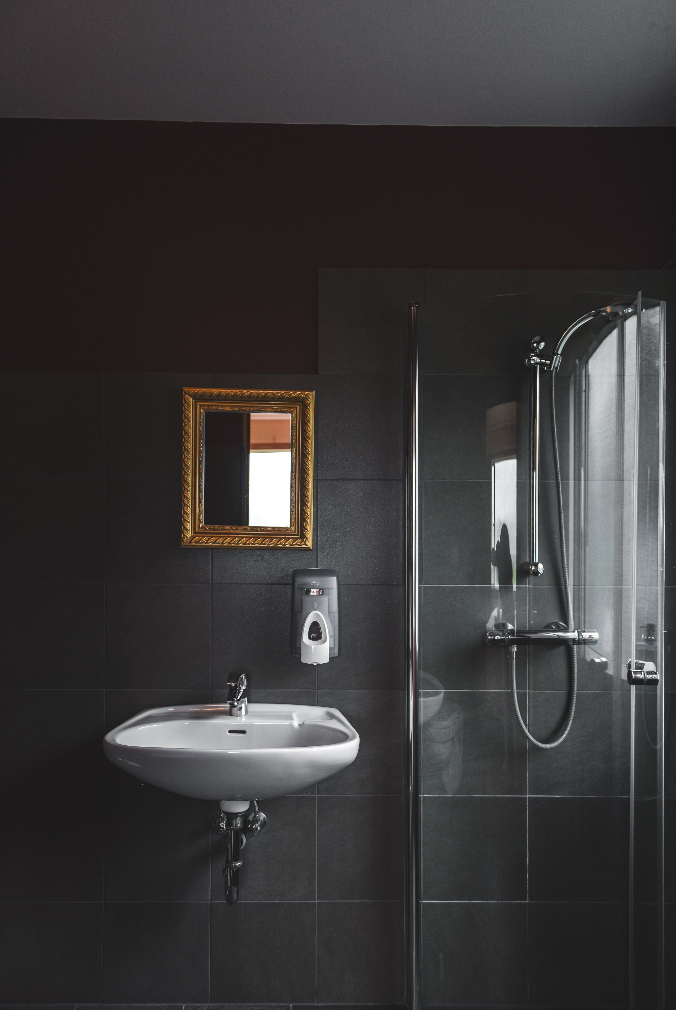 A modern bathroom with a white sink, a gold-framed mirror, and a glass shower enclosure.