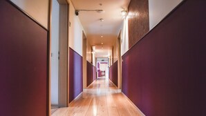 Un pasillo largo y estrecho con suelo de madera y paredes que alternan entre claros y oscuros.