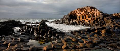A rocky coastal landscape with a large, irregularly shaped rock formation in the center.