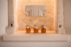A shelf with three jars of honey and a stone carving. - Neratze Hammam Suites (Rethymno)
