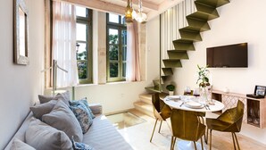 A modern living room with a sofa, dining table, and staircase.