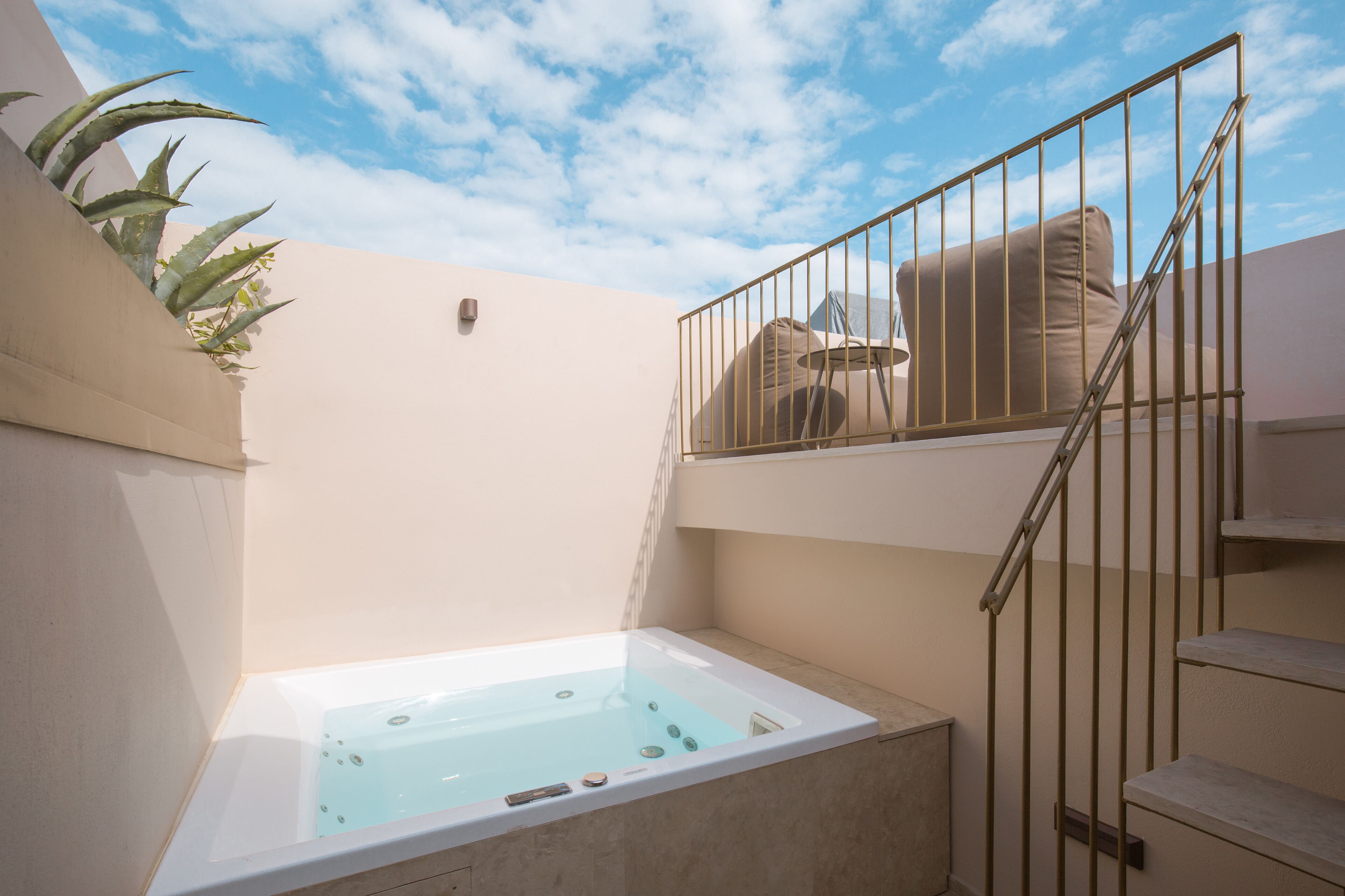 Un área de spa con un jacuzzi, una escalera y un balcón con una silla.