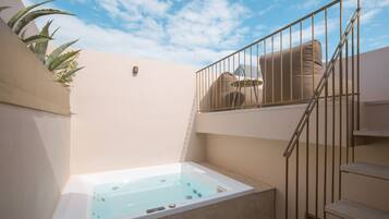Un área de spa con un jacuzzi, una escalera y un balcón con una silla.