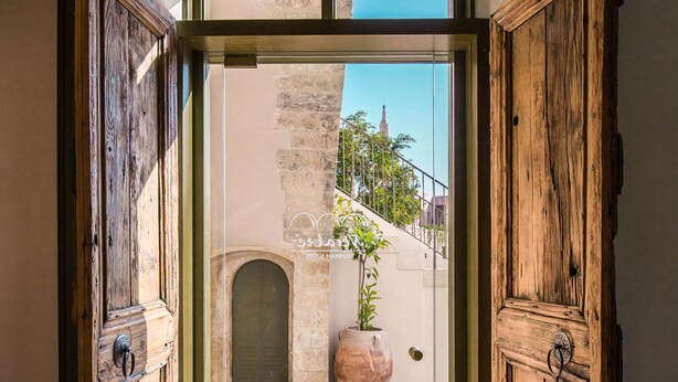 A doorway leading to a courtyard with a potted plant and a stone wall.