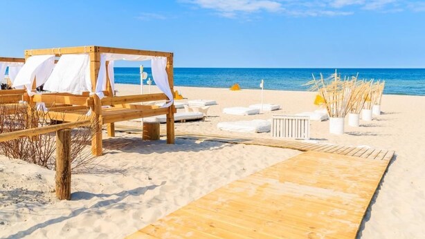 A beach setting with wooden structures, white canopies, and lounge chairs. - Villa Aqua BlueApart Jurata (Jurata)