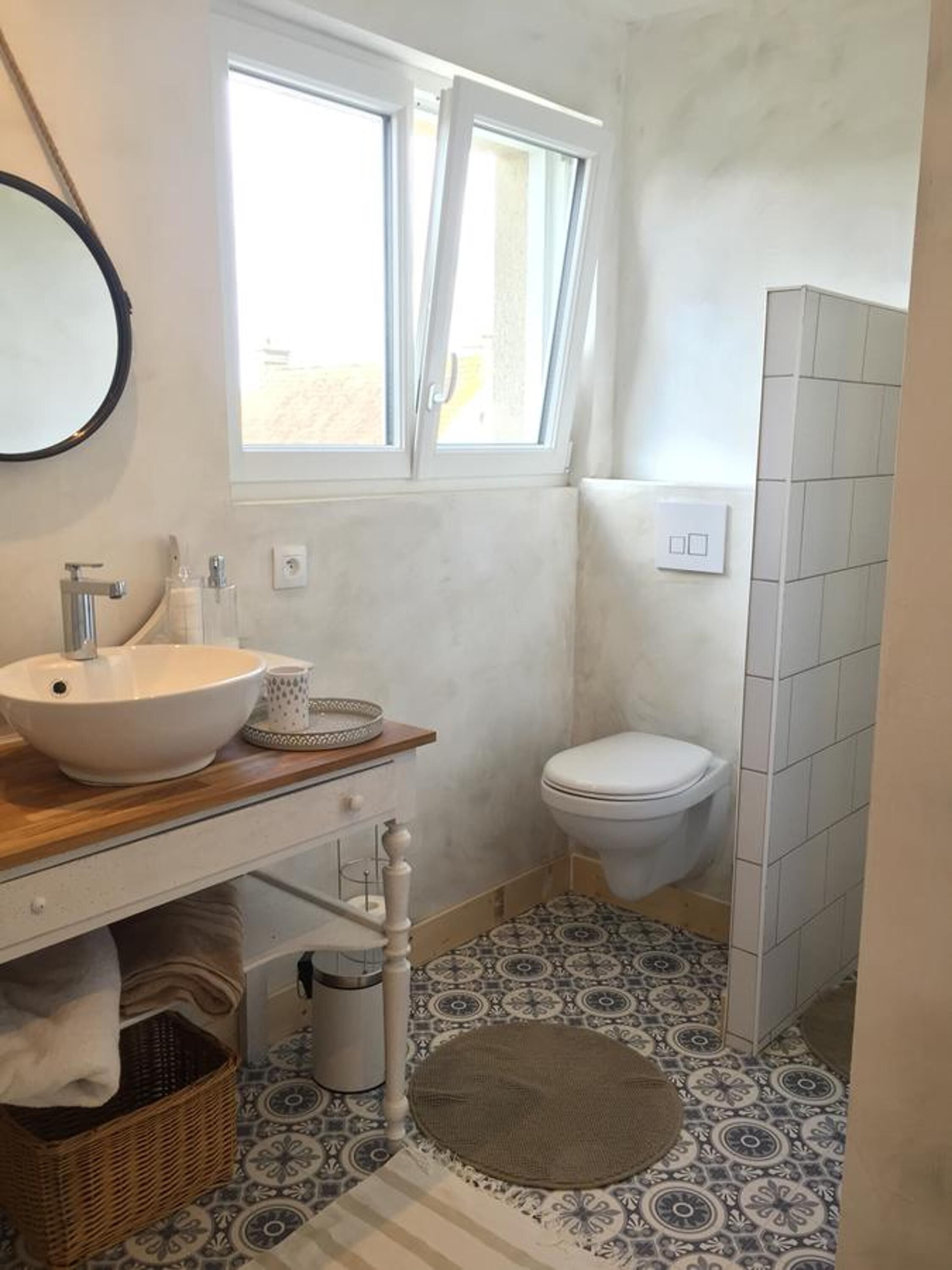 A small bathroom with a sink, toilet, and window.