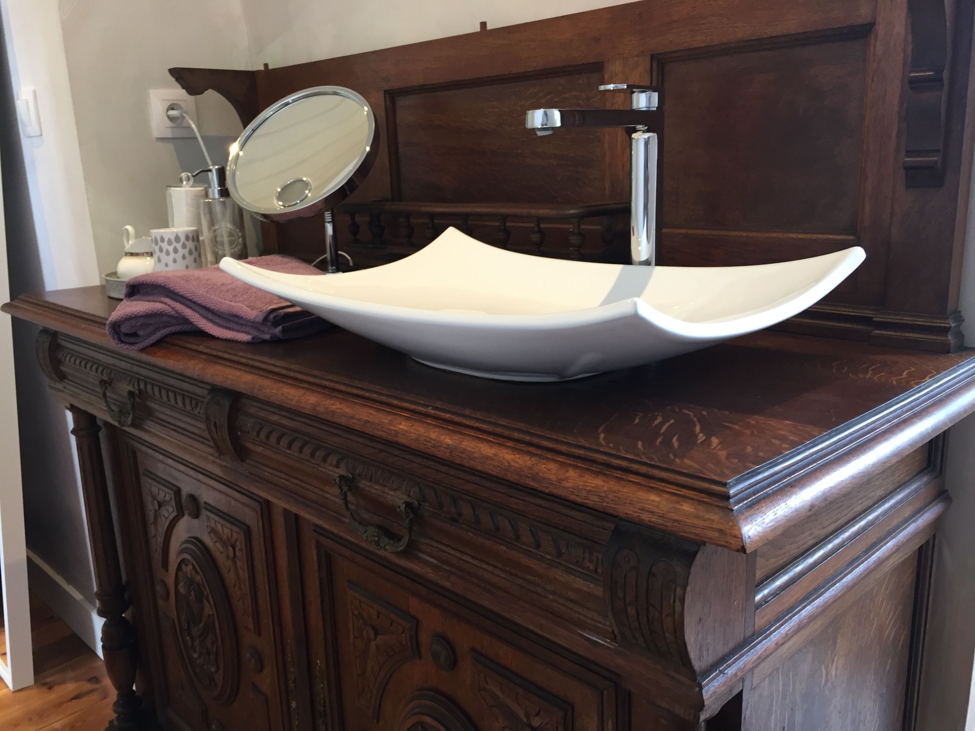 A wooden vanity with a white vessel sink, a mirror, and a towel.