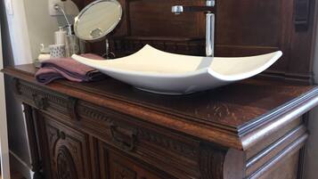 Un tocador de madera con un lavamanos blanco de estilo pedestal, un espejo y una toalla.