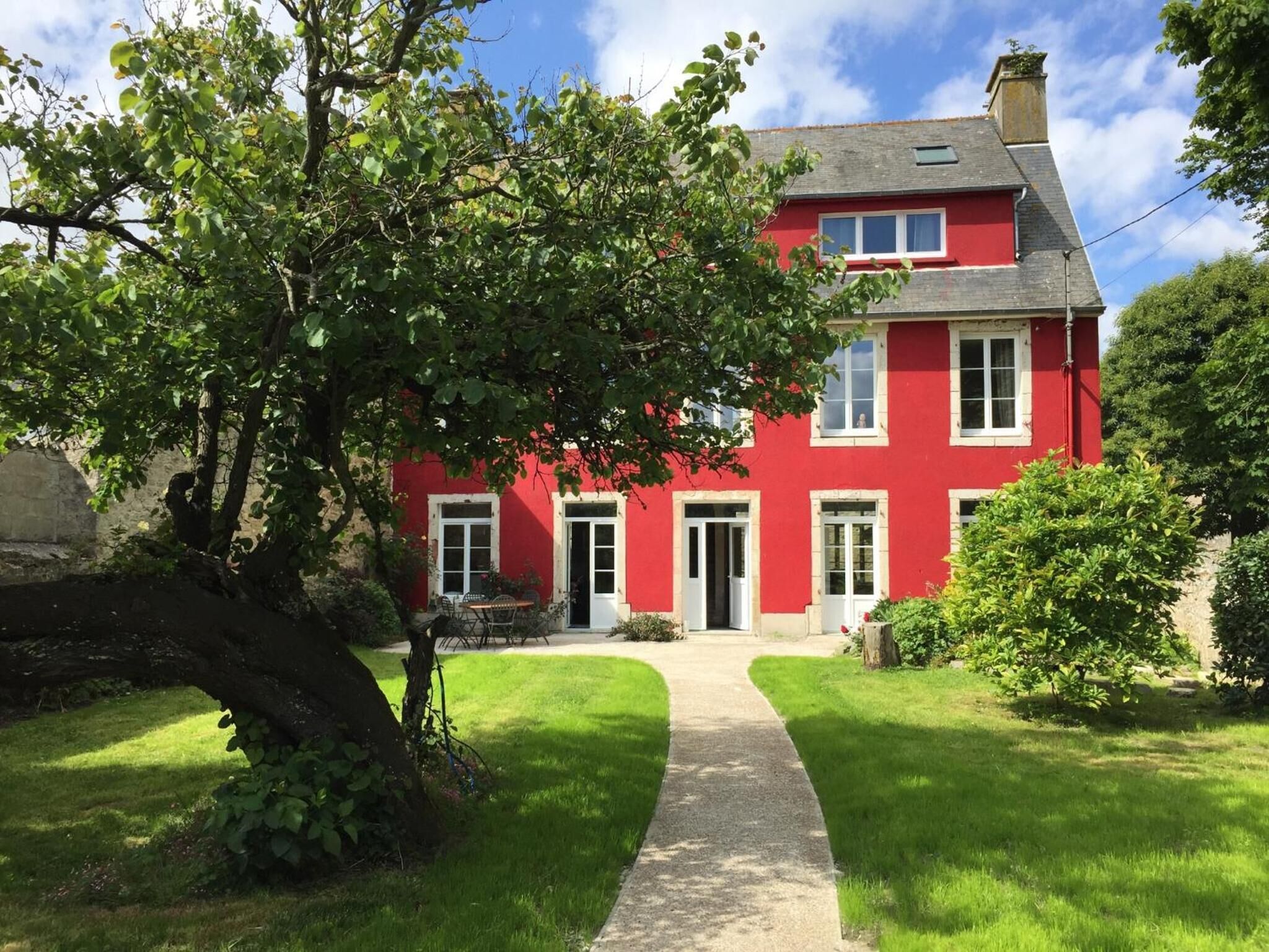 Una casa roja con entrada pavimentada y césped.