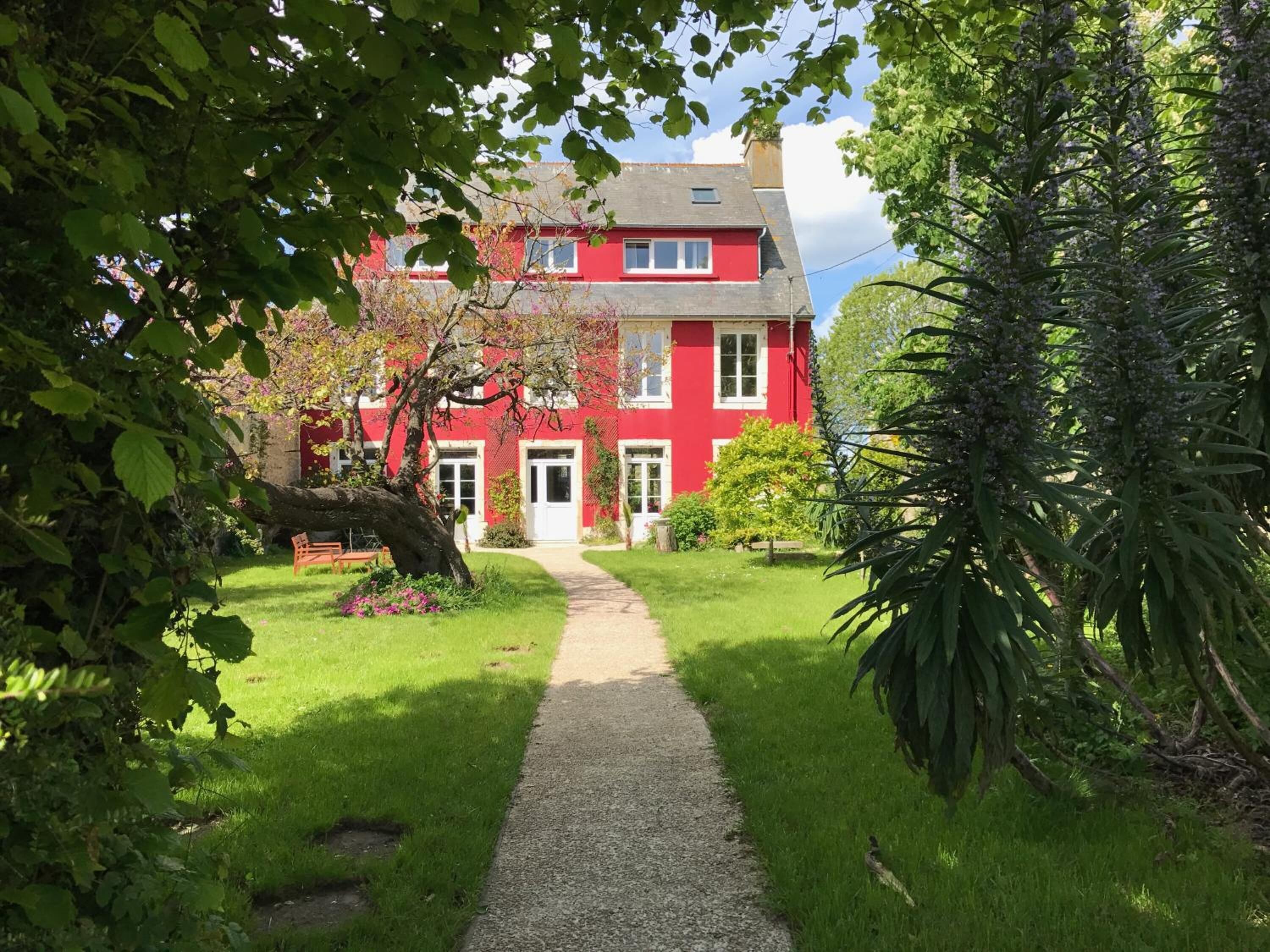 A red building with a paved pathway leading to the entrance.