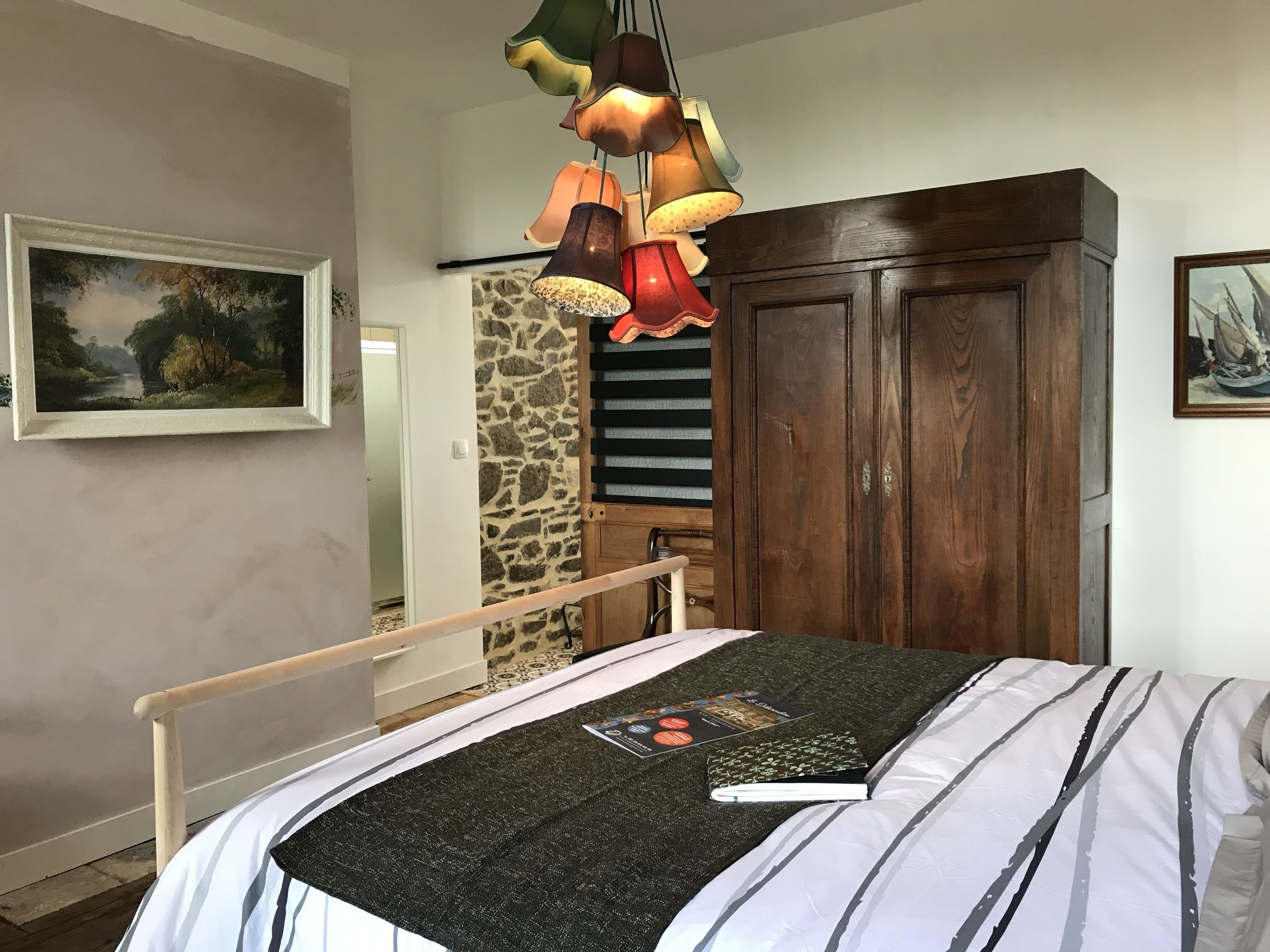 Un dormitorio con cama, armario de madera, pared de piedra y un cuadro en la pared.