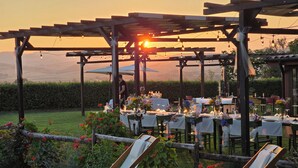 An outdoor dining area with tables set for a meal, surrounded by greenery and a wooden pergola. - Agriturimo Essentia Dimora Rurale (Larino)