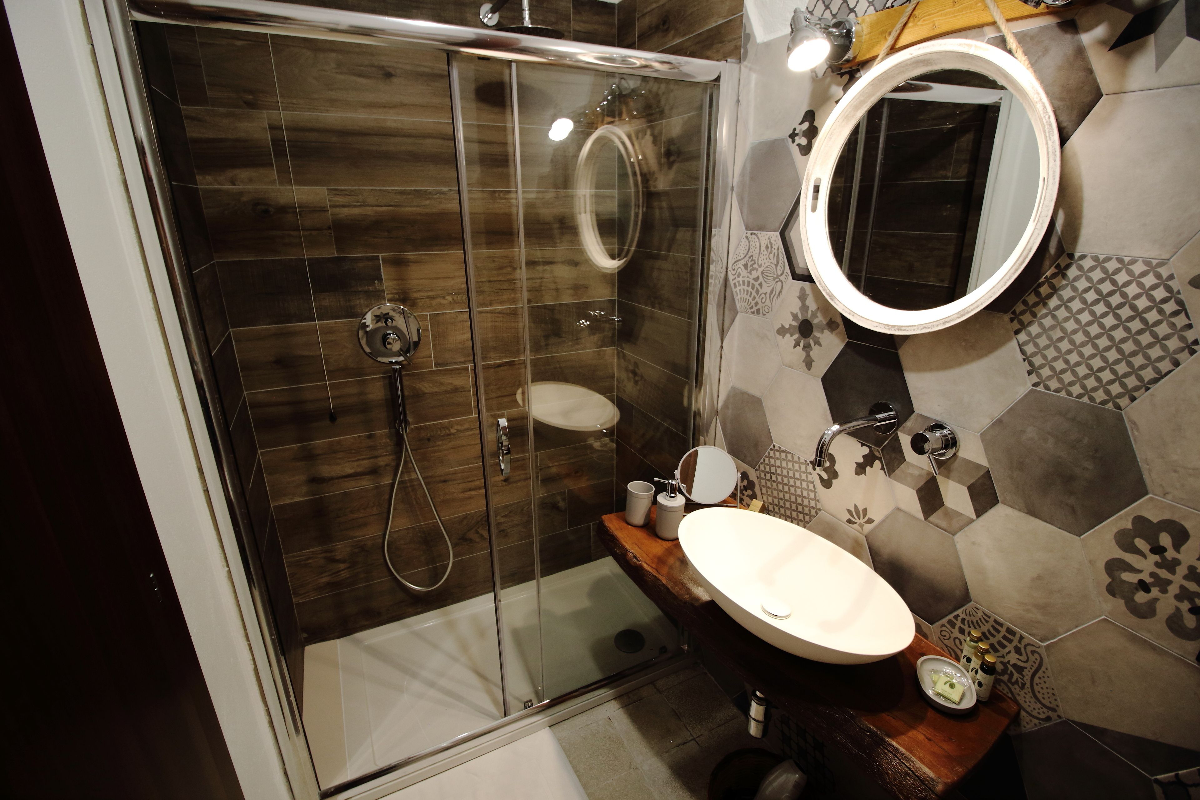 A modern bathroom with a glass-enclosed shower, a wooden vanity, and a large mirror.