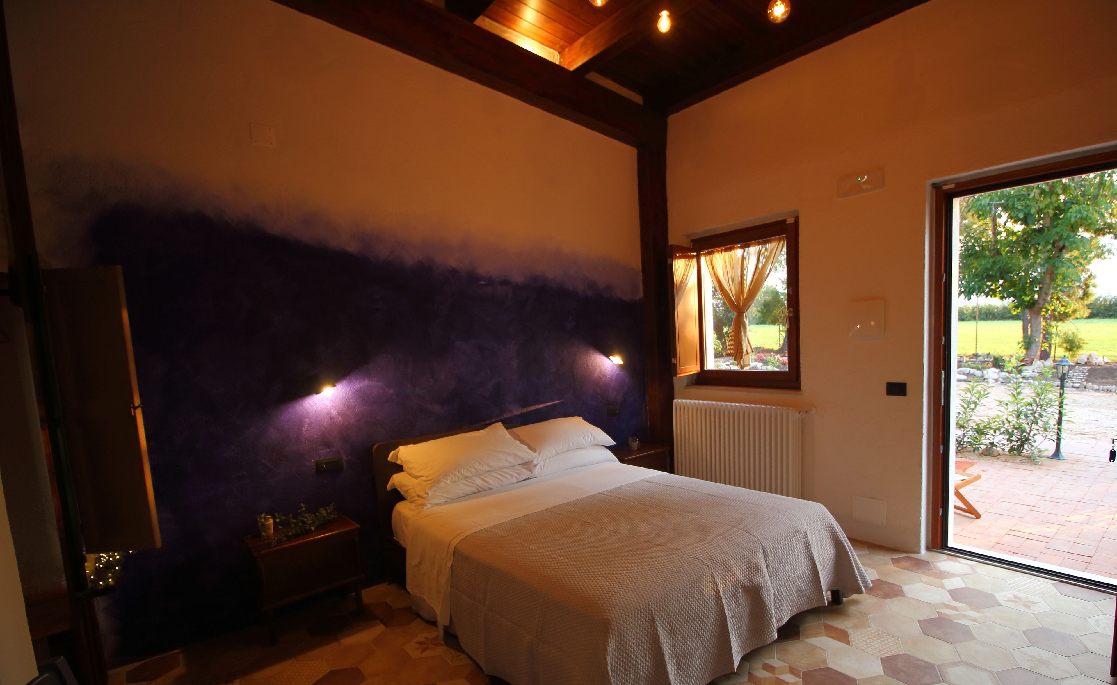 Une chambre à coucher comprenant un lit, une table de chevet, une fenêtre avec des rideaux et une vue sur l’extérieur.