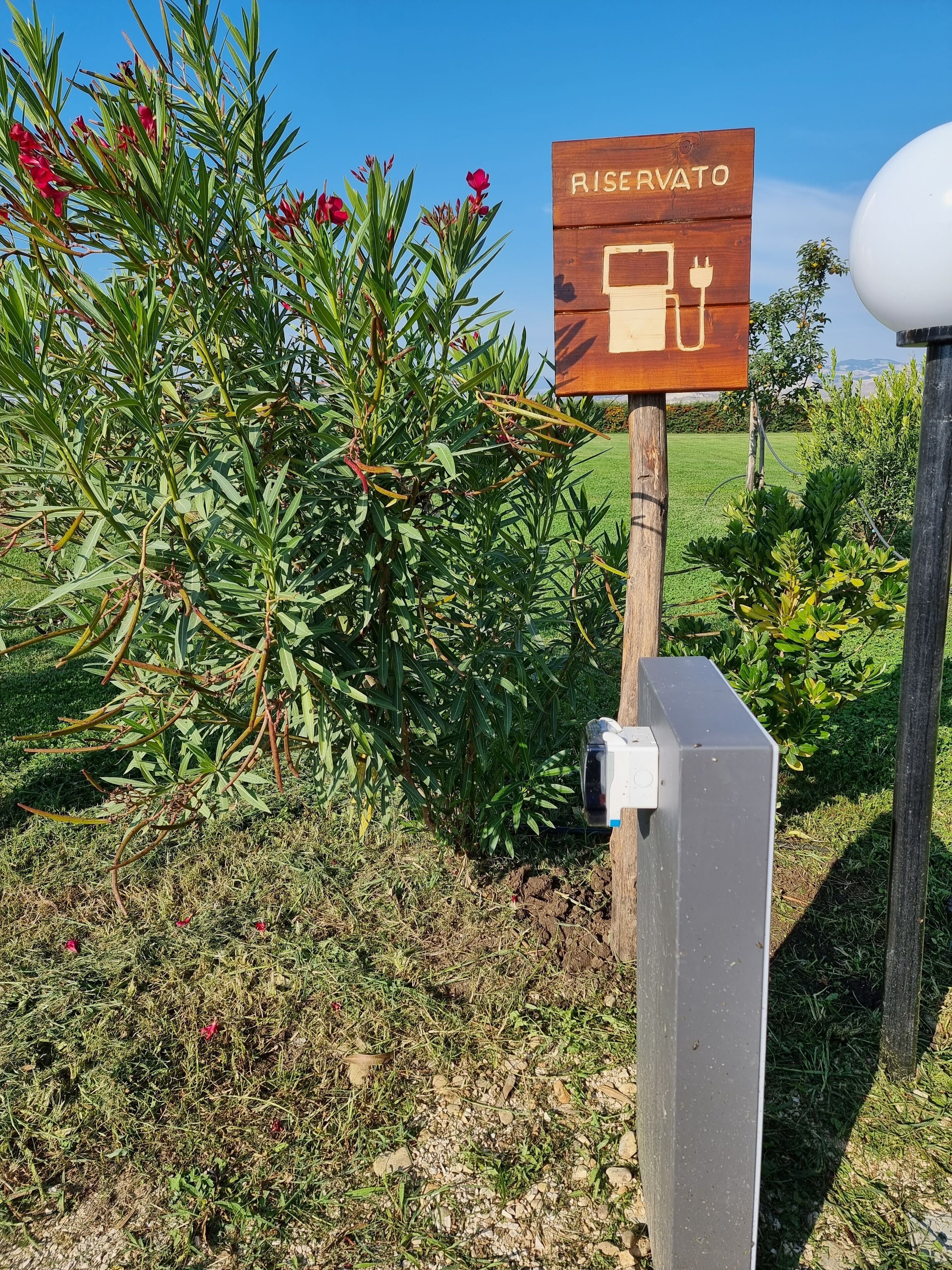 A sign with the word "RISERVATO" and a plug symbol, indicating a reserved parking area.
