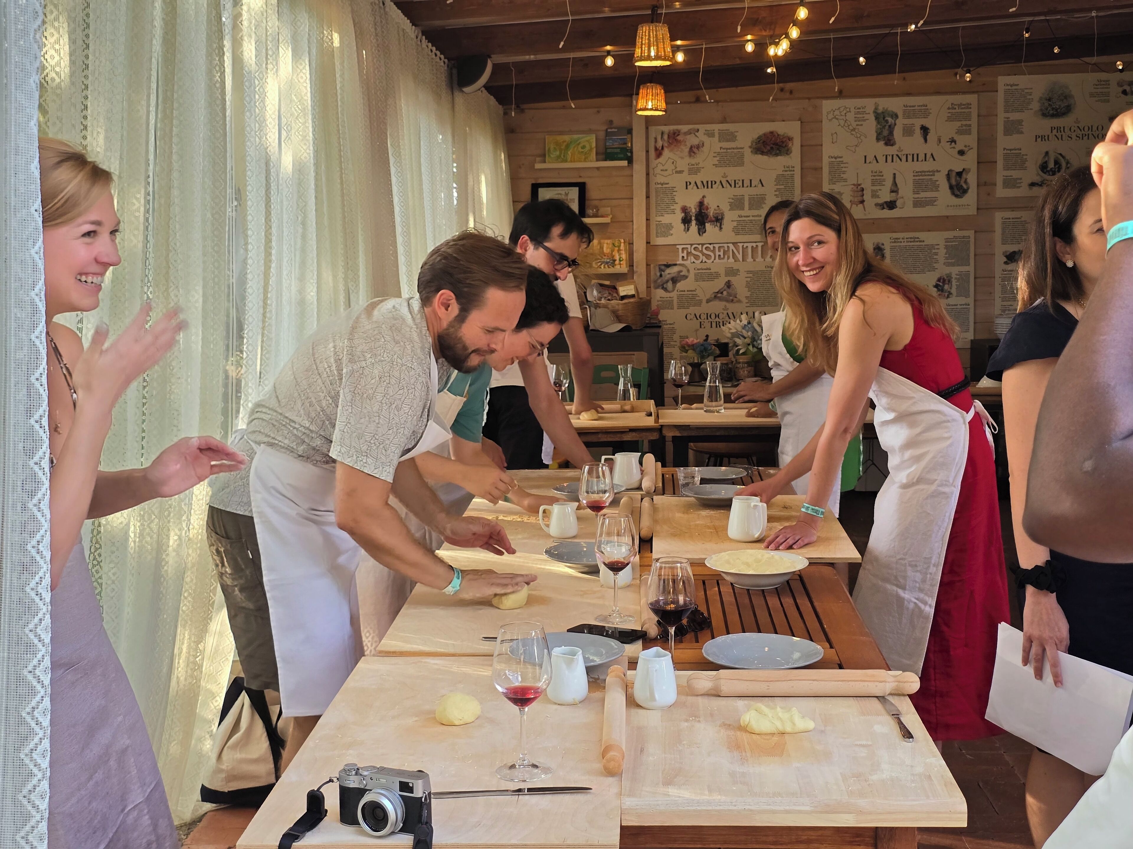 A group of people engaged in a cooking activity at a wooden table with various kitchen tools and ingredients.