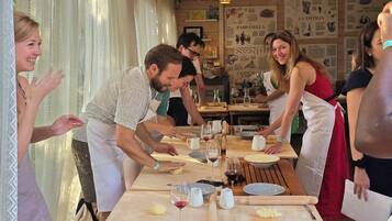 A group of people engaged in a cooking activity at a wooden table with various kitchen tools and ingredients.