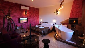 A modern bedroom with a large bed, a sitting area with a glass table, and a bathtub. - Agriturimo Essentia Dimora Rurale (Larino)