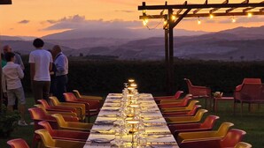 A long dining table set for a meal with chairs on both sides, overlooking a mountainous landscape. - Agriturimo Essentia Dimora Rurale (Larino)