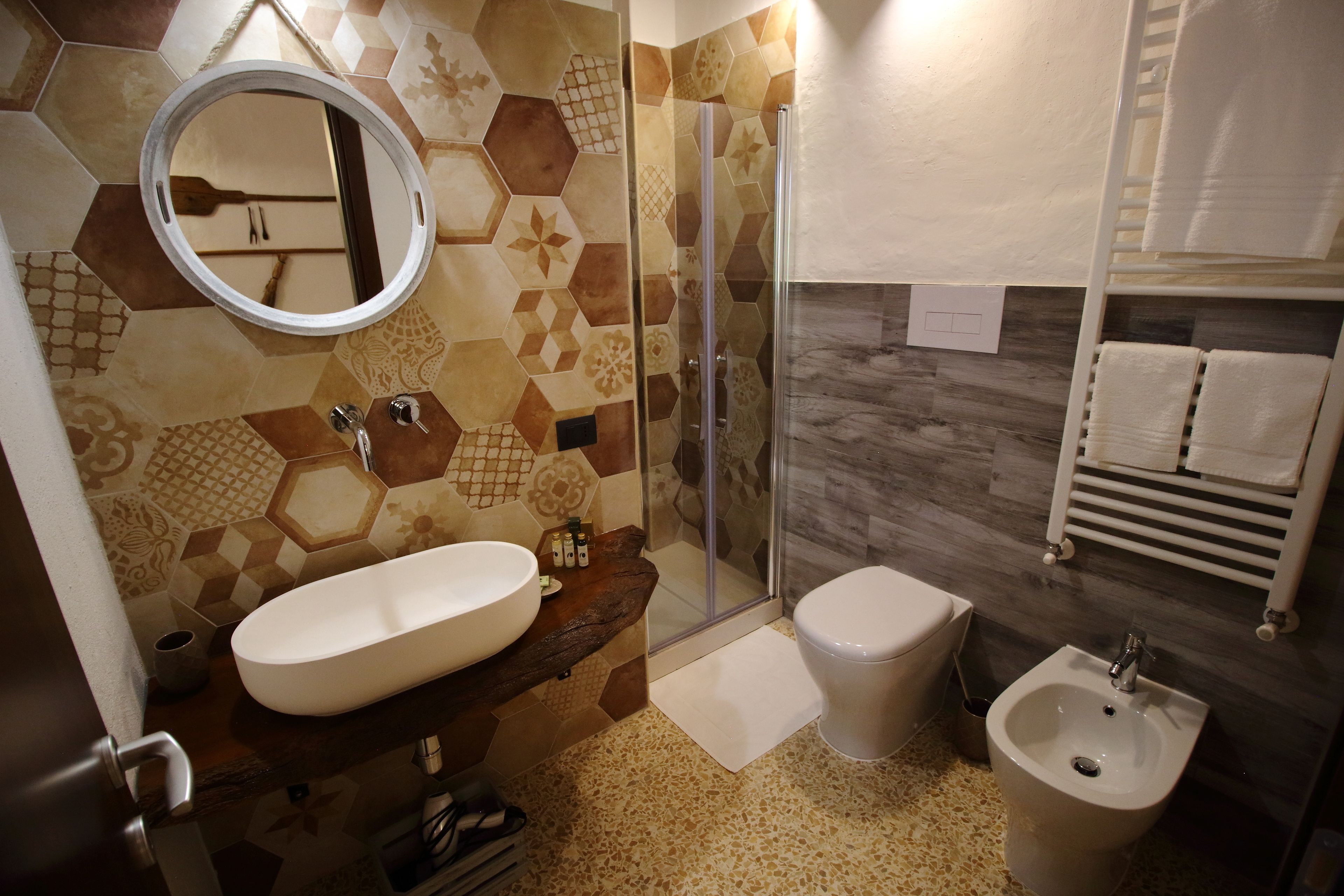 Un baño con espejo redondo, lavabo, bidé y zona de ducha.