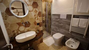 Un baño con espejo redondo, lavabo, bidé y zona de ducha.