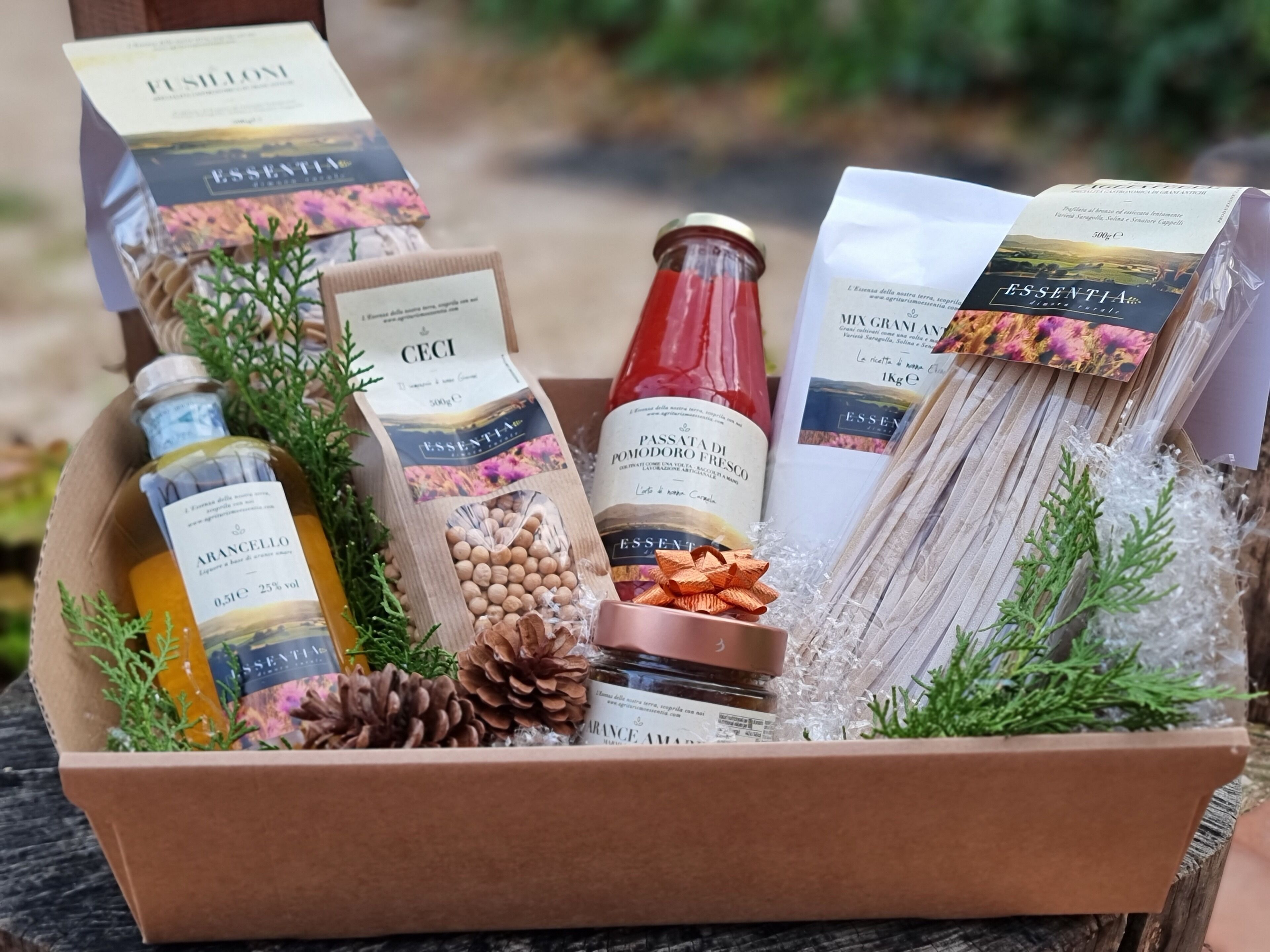 A gift basket containing various food items and a bottle of wine, placed on a wooden surface.