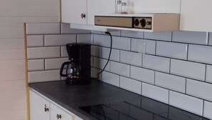 Una cocina compacta con armarios blancos, una encimera negra y un horno integrado.