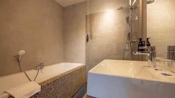 A modern bathroom with a bathtub, a large sink, and a shower.